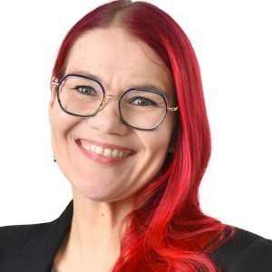Portrait of Riikka Arffman. Riikka has long red hair and a wide smile.