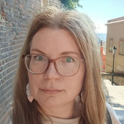 Portrait of Ulla Saarela. Ulla has light brown hair, glasses and beige shirt.